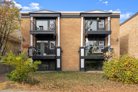 a brick apartment building with three balconies and a lawn